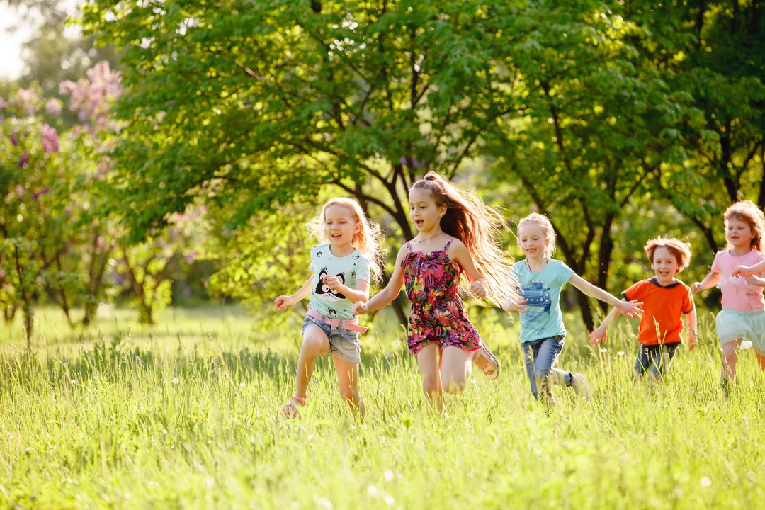 group of young children running in a field.